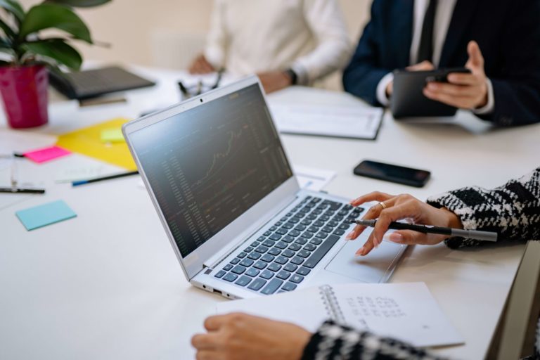 Fotografia retratando uma pessoa manuseando um notebook. Na tela do notebook são apresentados gráficos de crescimento após a aplicação de práticas de SEO.